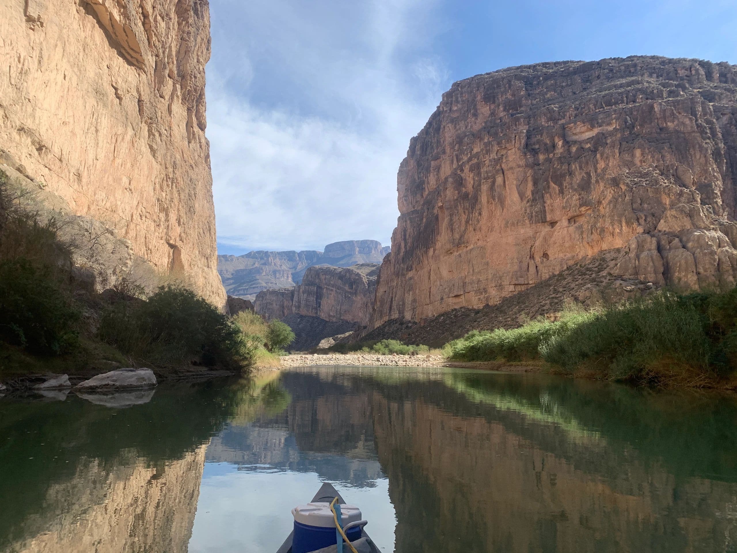 Canyon walls and their reflection with a canoe bow in the foreground